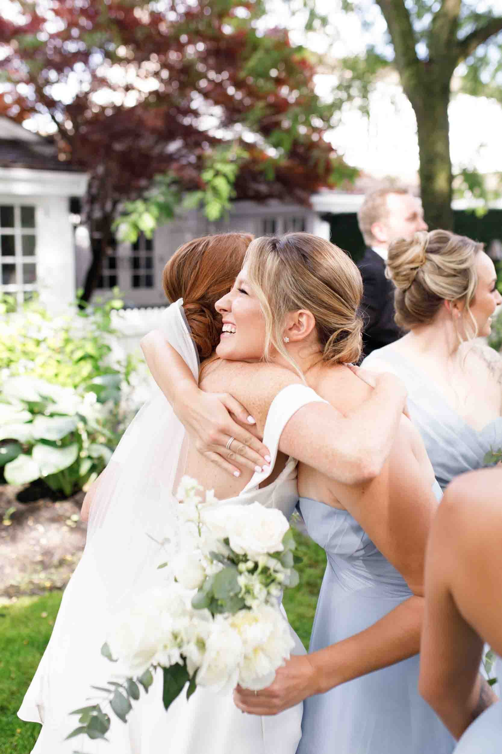Bridesmaids embracing in garden courtyard at The Doctor’s House in Kleinburg, Ontario