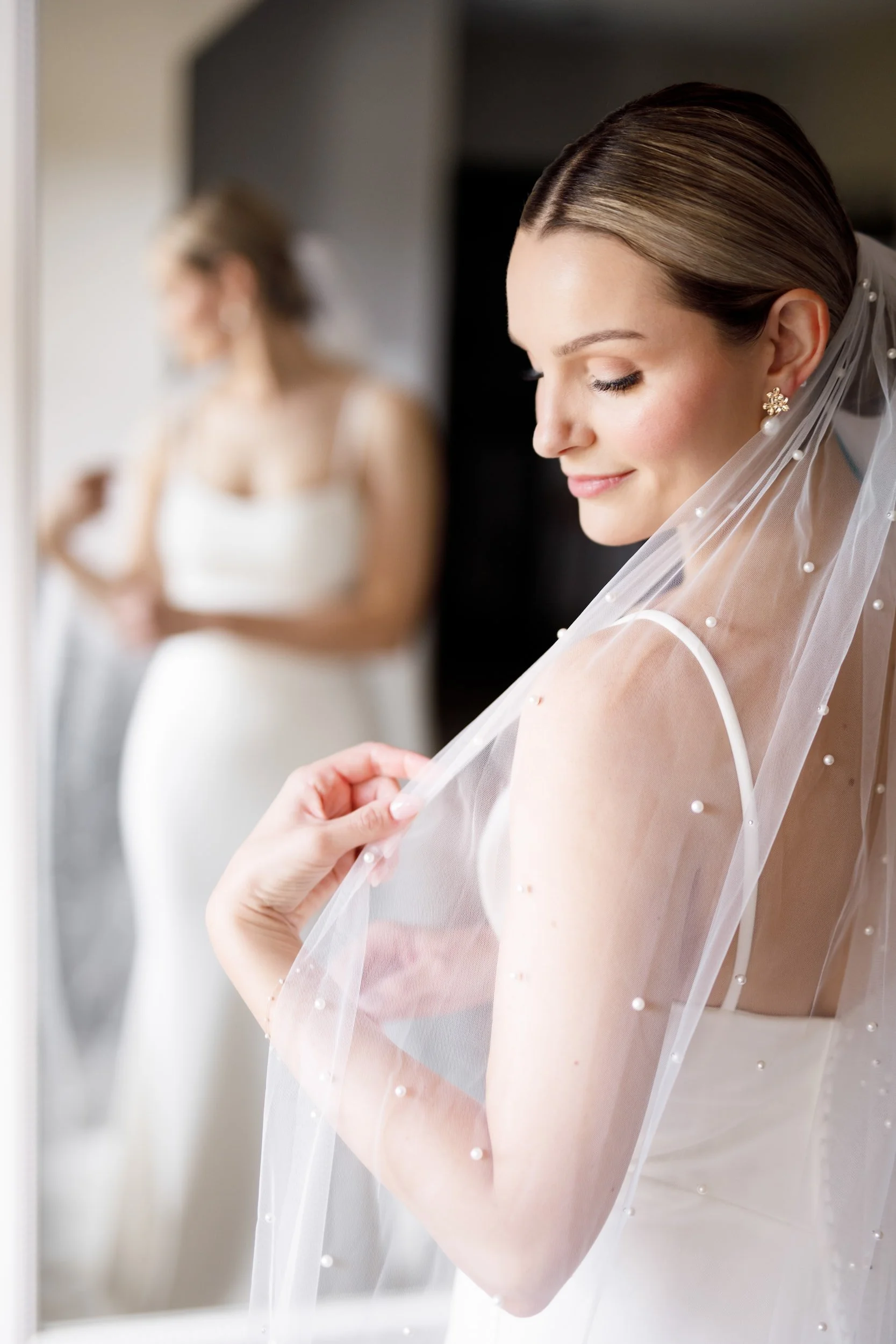 Close-up bridal portrait adjusting veil before The Manor Event Venue wedding in King, Ontario