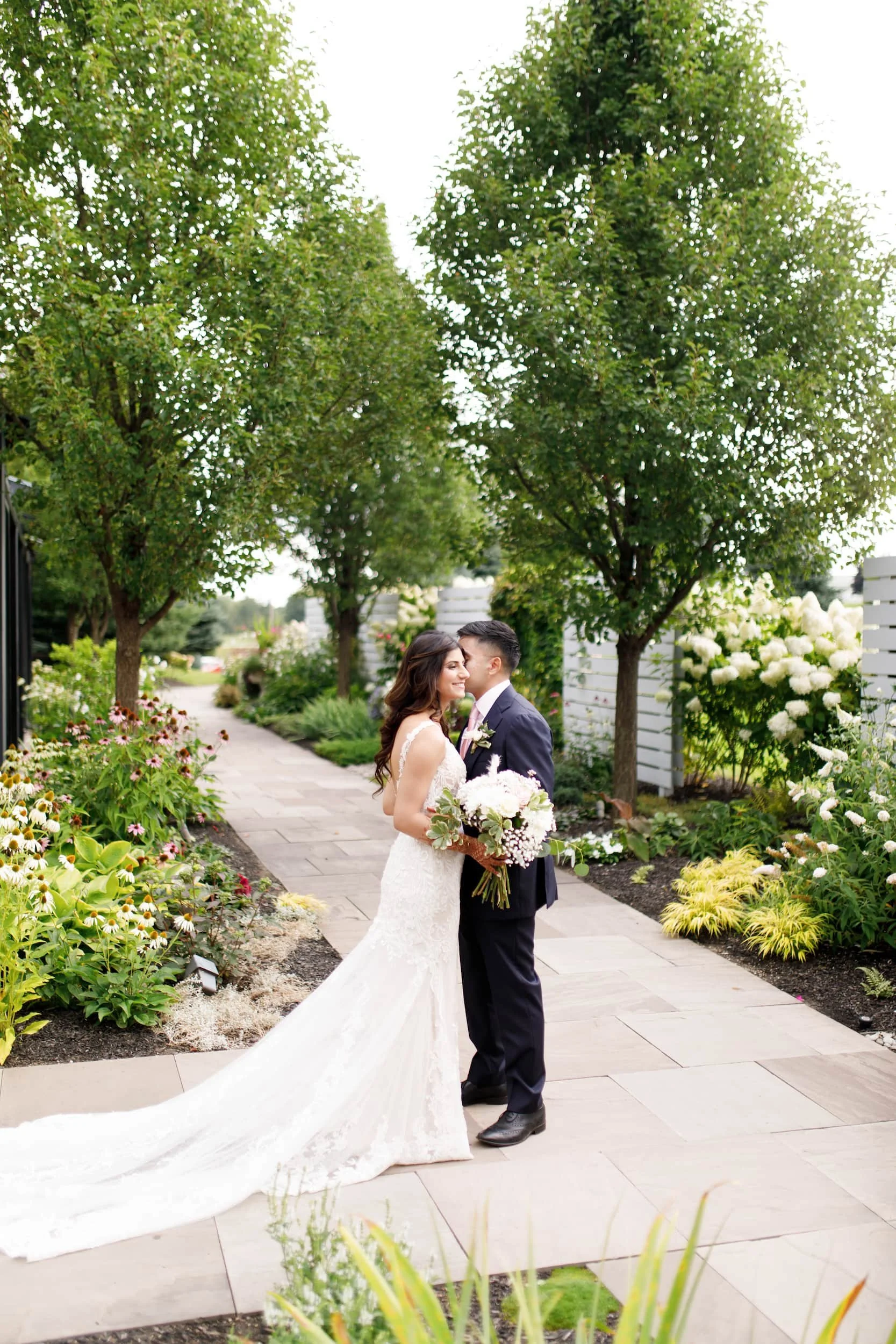 Bride and groom walking through garden pathway at Whistle Bear Golf Club wedding in Cambridge, Ontario