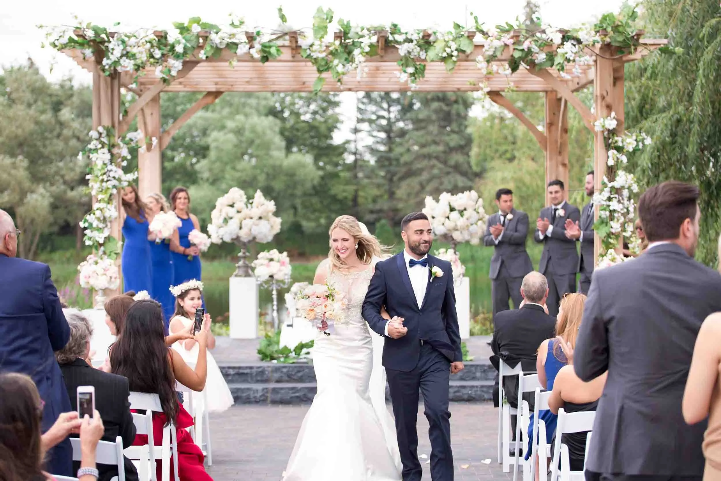 Bride and groom recessional beneath the Arlington Estate wooden pergola in Vaughan