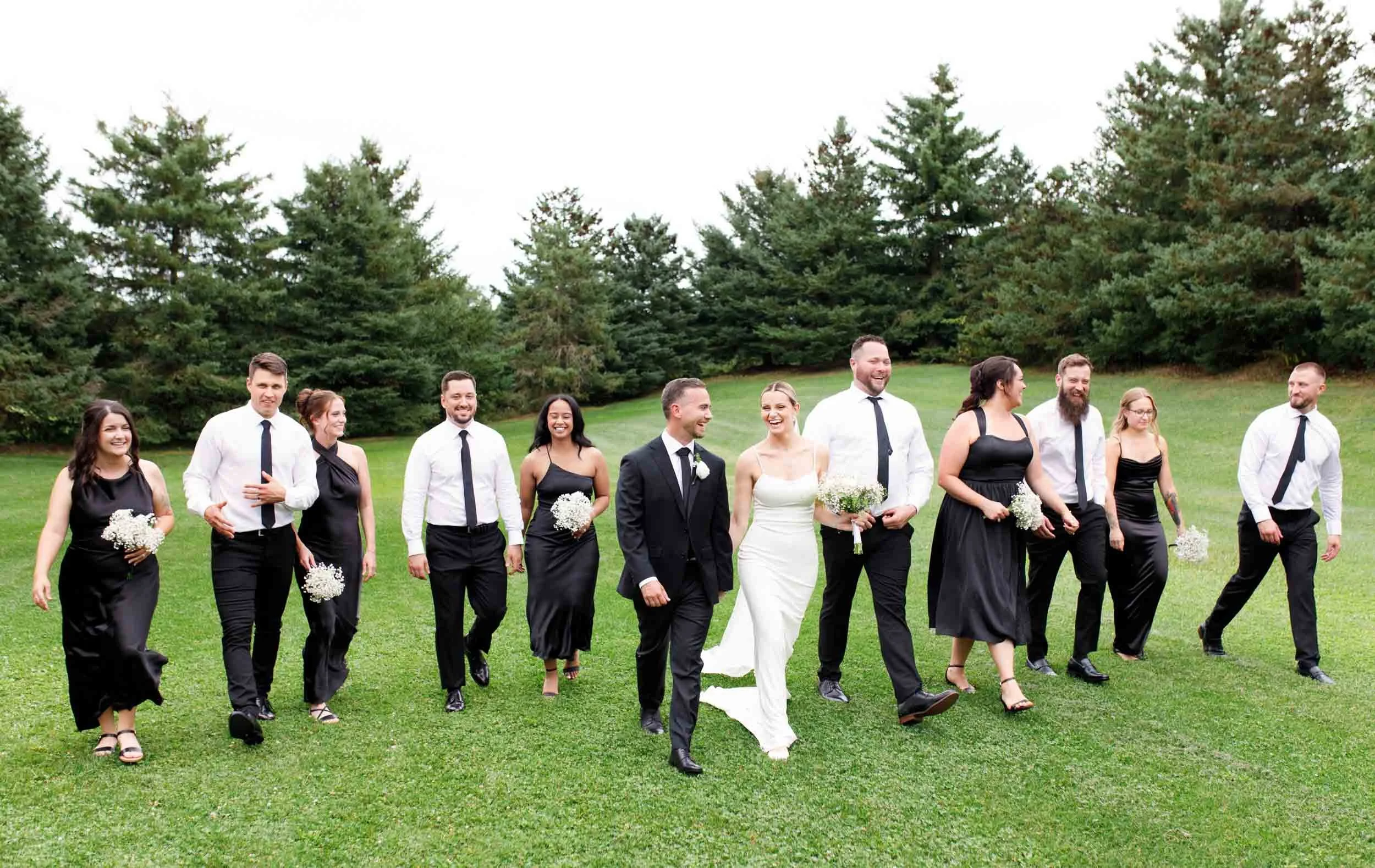 Wedding party walking across lawn after ceremony at The Manor Event Venue in King, Ontario