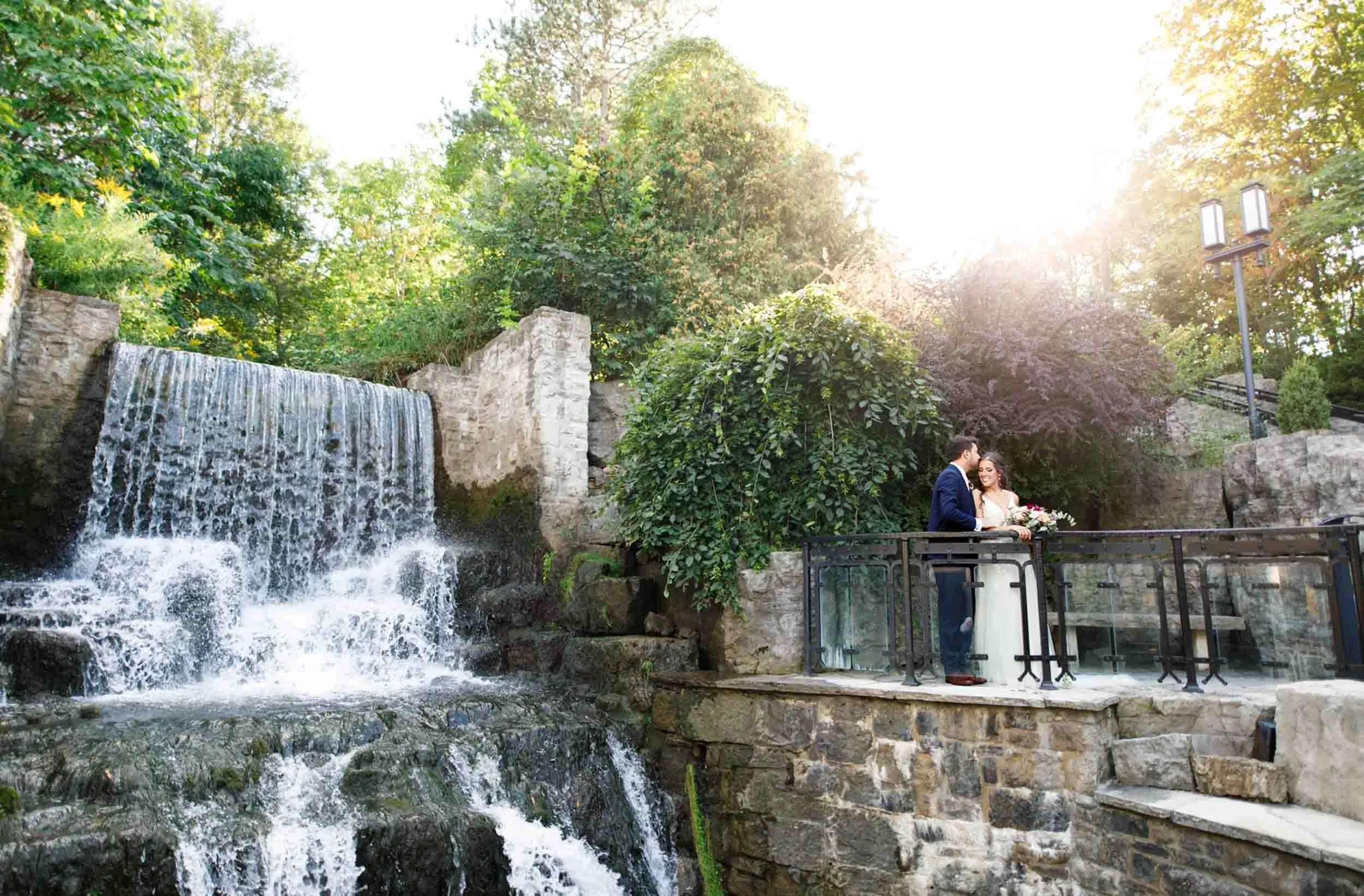 Bride and groom portrait by the waterfall at the Ancaster Mill in Ancaster
