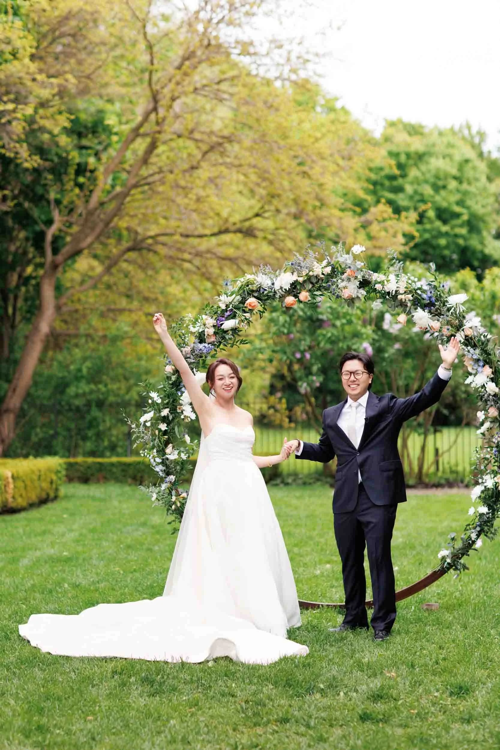 Bride and groom celebrating under floral arch at Graydon Hall Manor