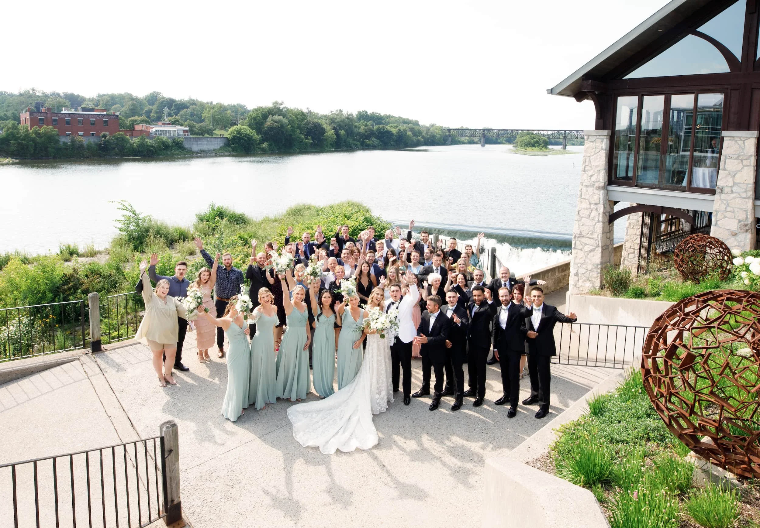 Wedding party celebrating on riverside terrace at Cambridge Mill overlooking the Grand River