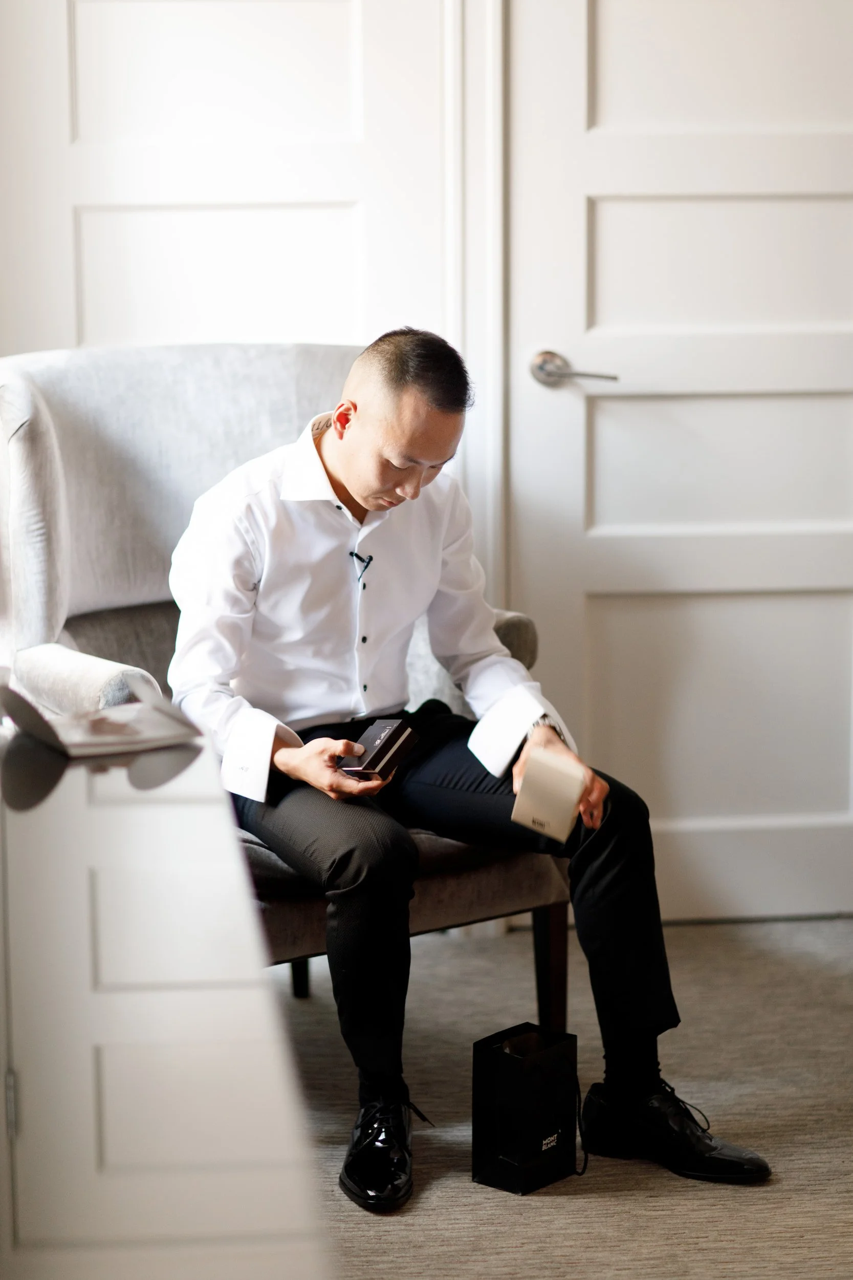 Groom getting ready and checking phone in hotel suite before wedding at Omni King Edward Hotel Toronto
