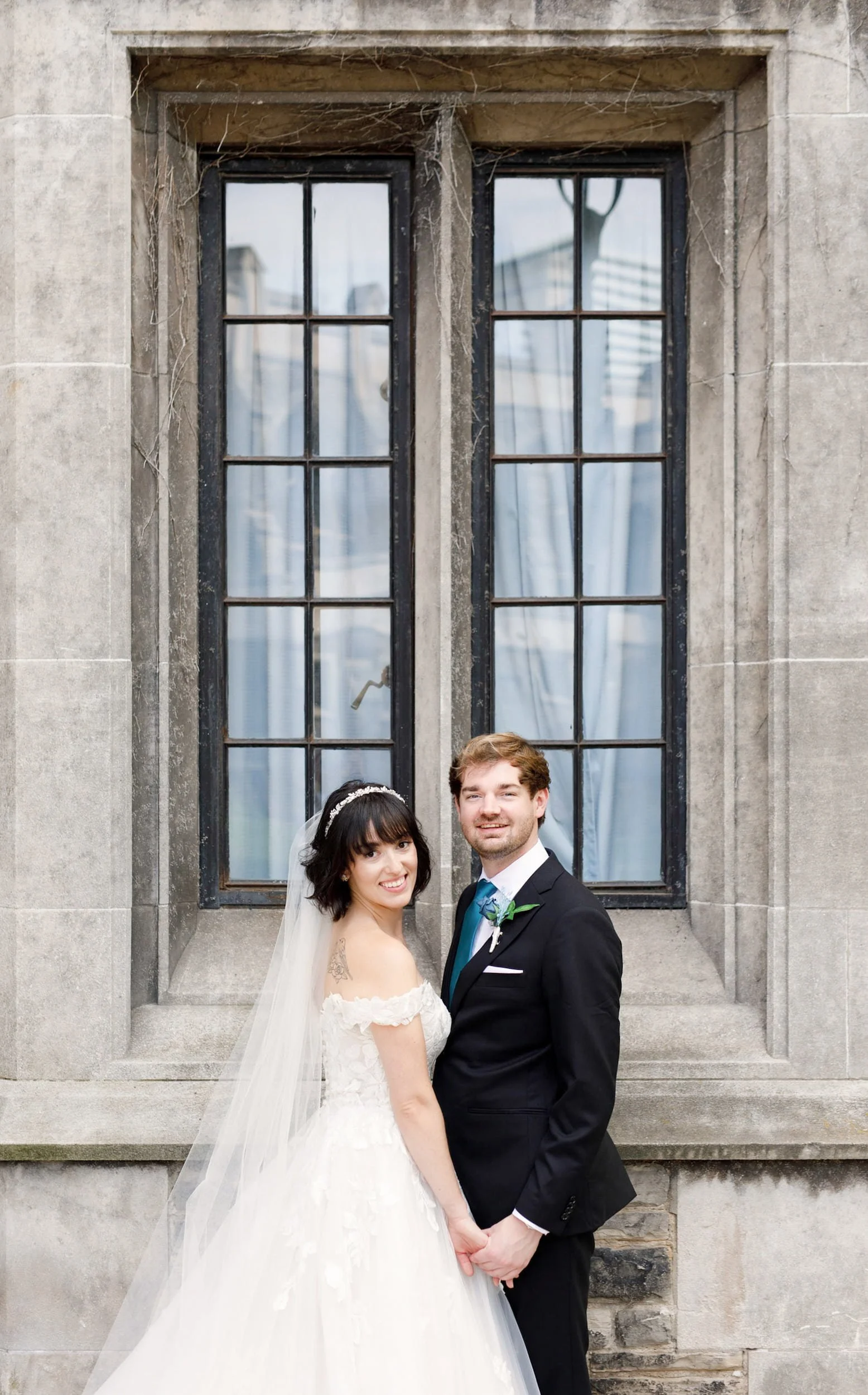 Bride and groom portrait beside stone window at Victoria College, University of Toronto in Toronto, Ontario