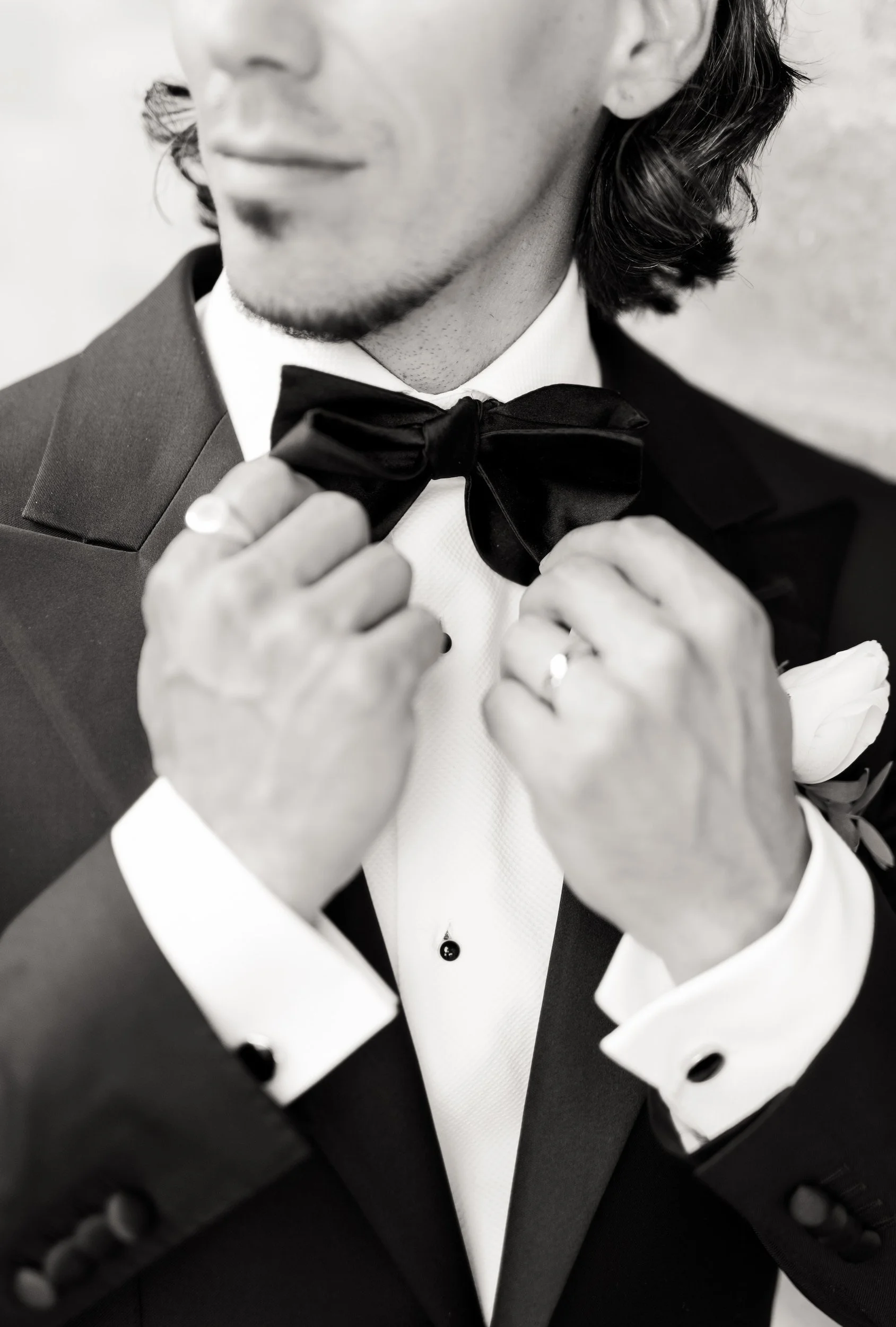 Black and white portrait of groom adjusting bow tie during wedding preparations at The Manor Event Venue in King, Ontario