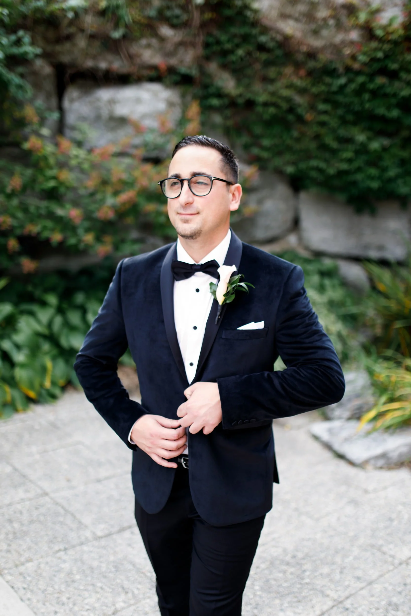 Groom adjusting tuxedo jacket during wedding portraits at The Manor Event Venue in King, Ontario
