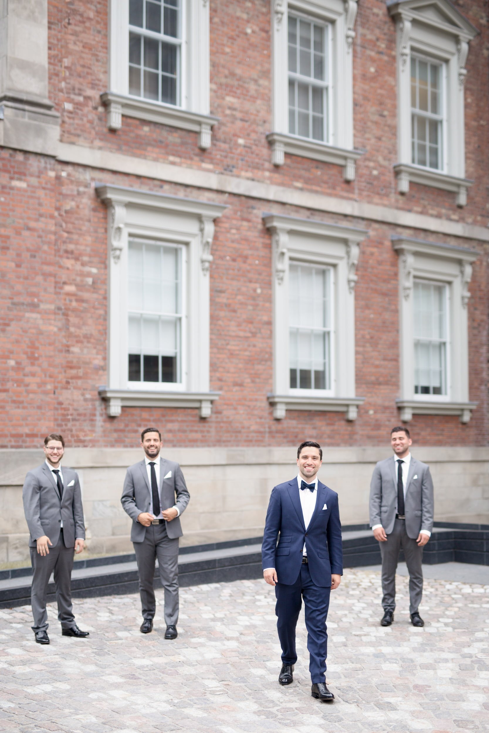 Groom with groomsmen against Victorian brick façade at Osgoode Hall in Toronto