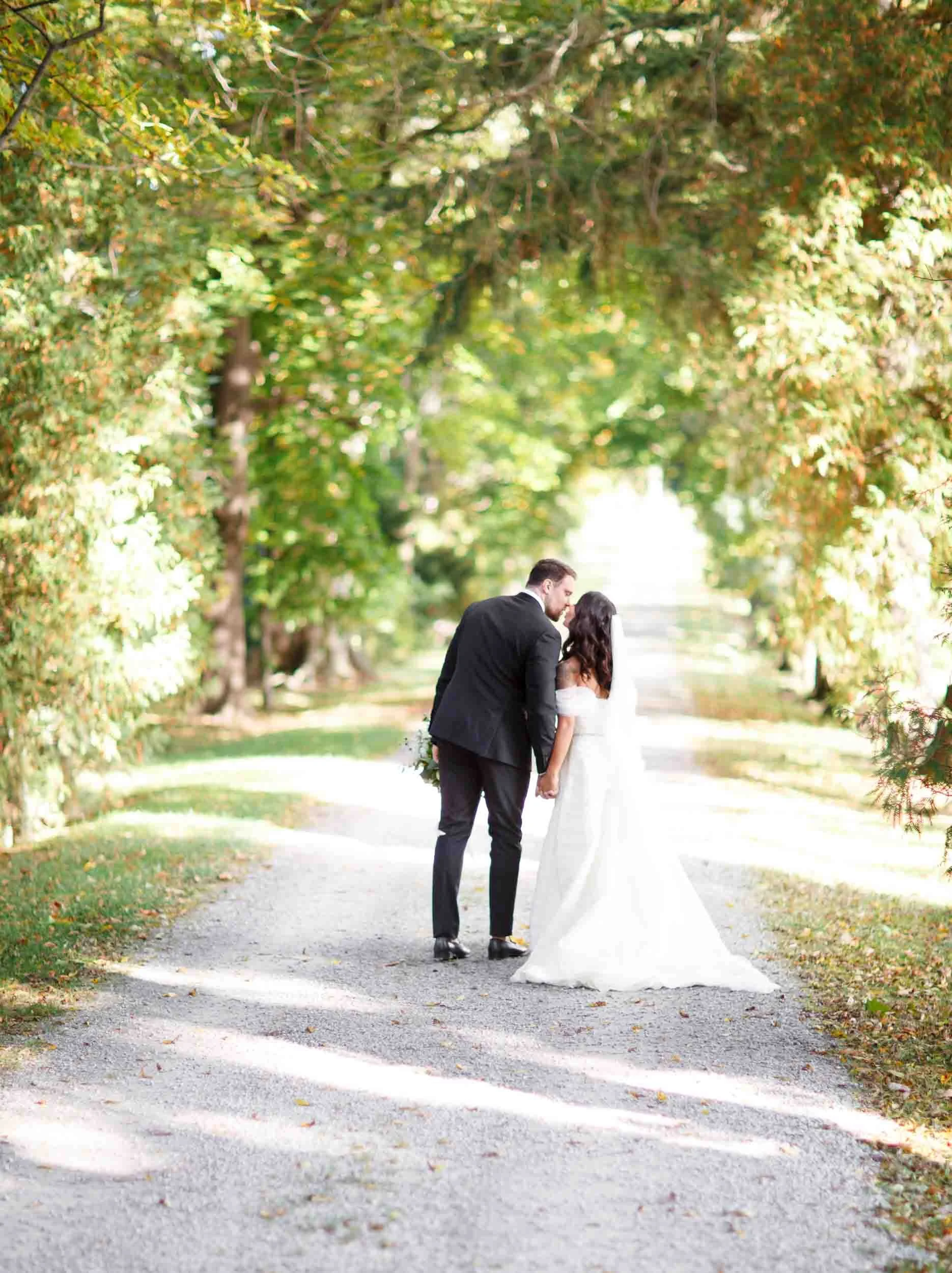 Bride and groom walking beneath orchard trees at Kurtz Orchards