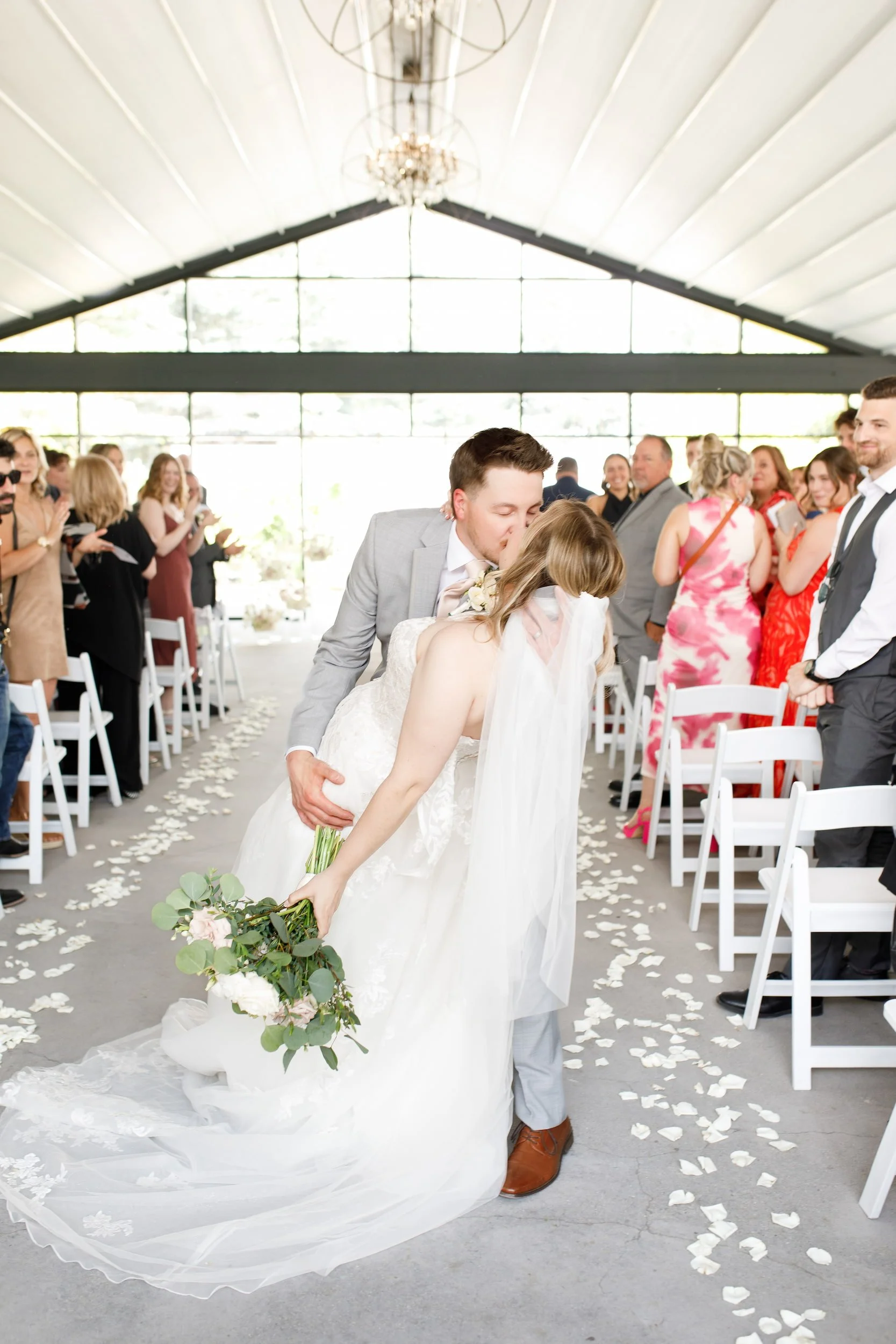 Newlyweds walking down the aisle as guests celebrate at Whistle Bear Golf Club in Cambridge, Ontario