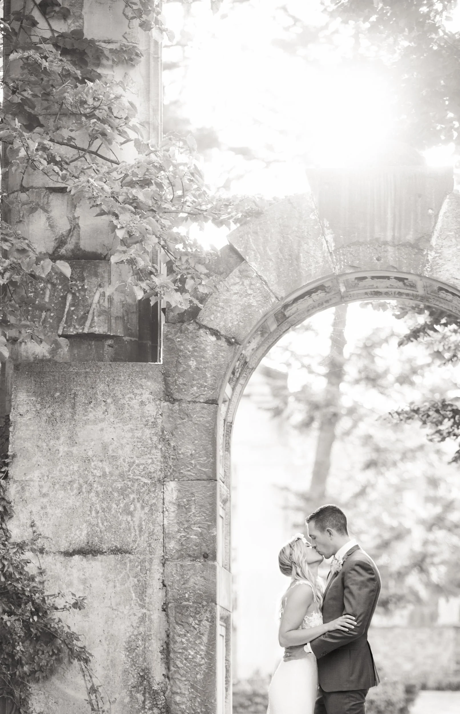 Romantic black and white portrait beneath Guild Inn Estate stone arch