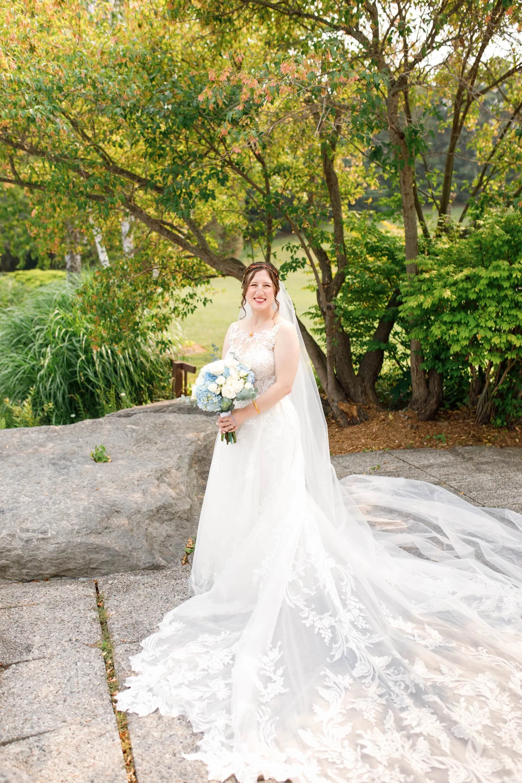 Bride holding bouquet on stone terrace overlooking the grounds at The Manor Event Venue wedding in King, Ontario