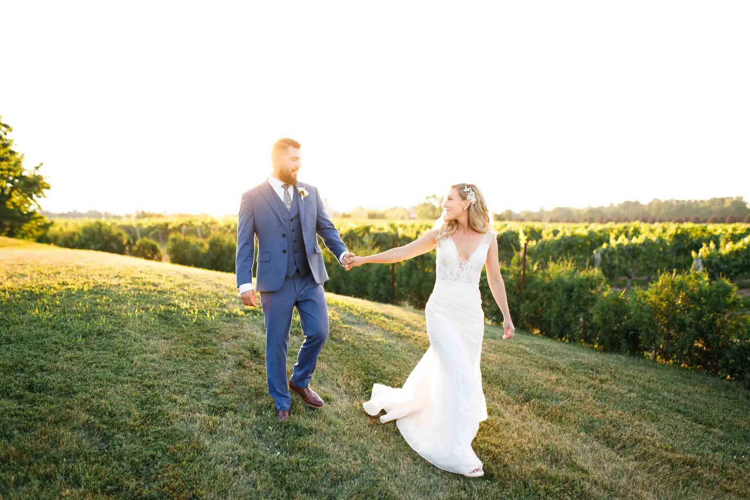 Bride and groom walking through the vineyards at Kurtz Orchards in Niagara-on-the-Lake