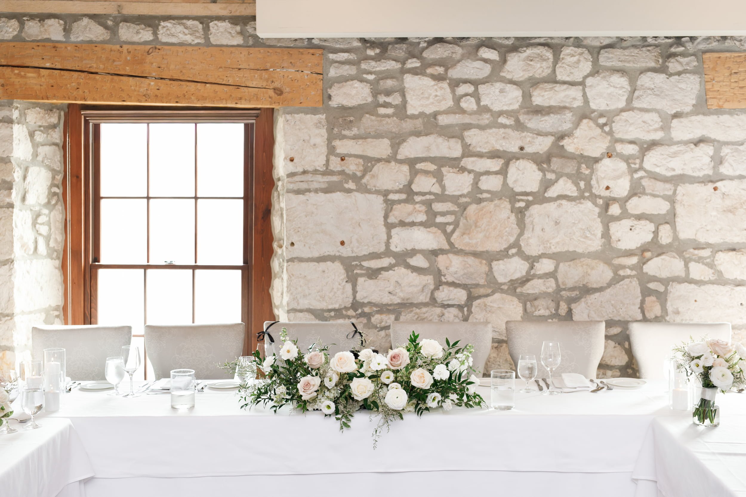 Reception head table against historic limestone wall at Cambridge Mill in Cambridge, Ontario