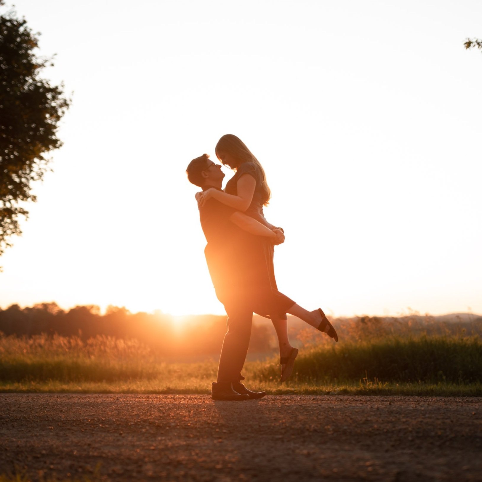 Couple lifting and embracing during their sunset engagement session at Bannockburn 1878 in Clinton, Ontario