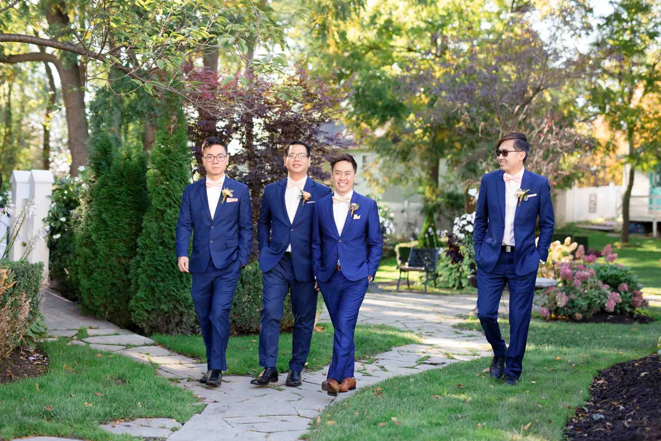 Groomsmen walking along stone pathway at The Doctor’s House wedding in Kleinburg, Ontario