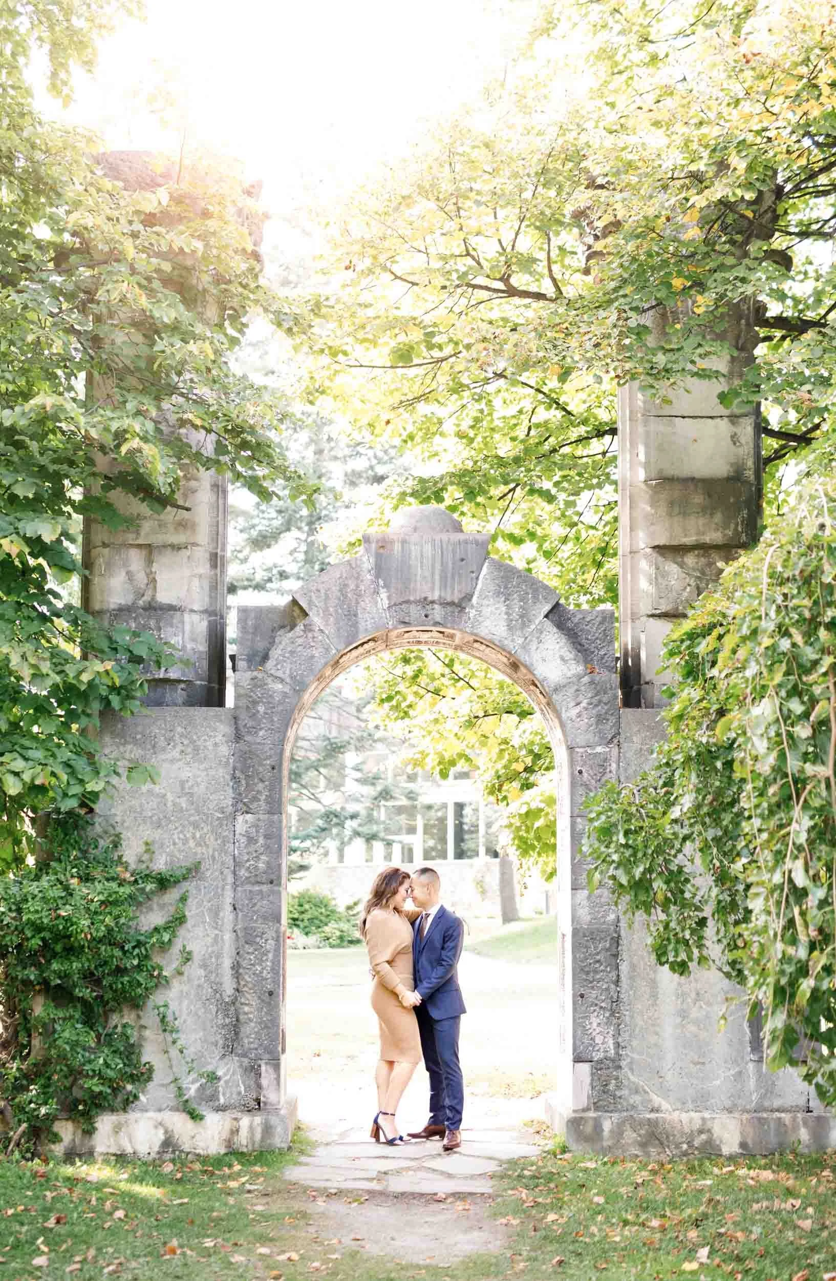 Engagement portrait framed by stone arch at Guild Inn Estate in Scarborough