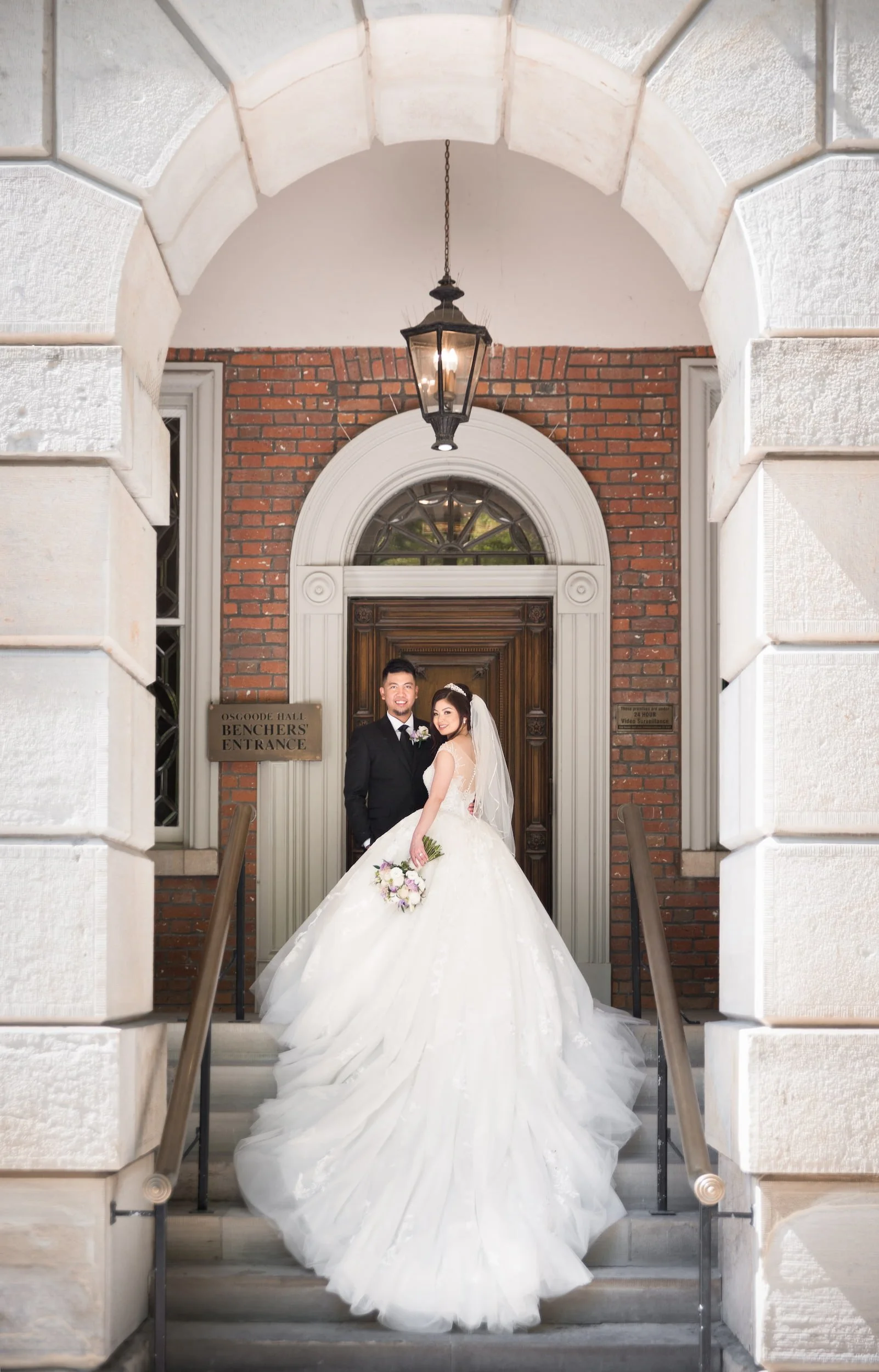 Bride and groom framed by arched entrance at Osgoode Hall in Toronto