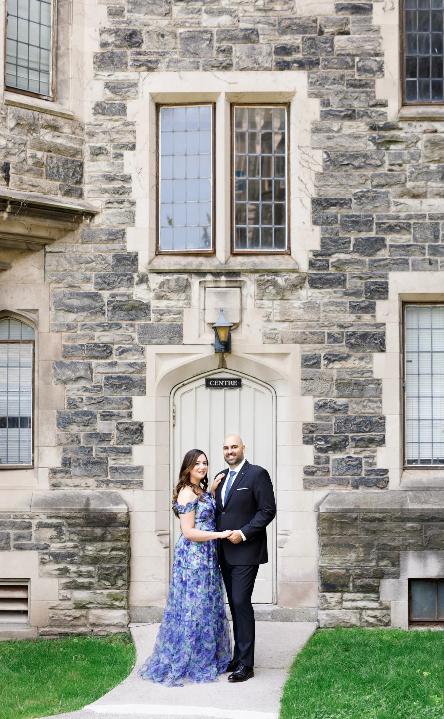 Couple standing outside historic stone facade at Knox College, University of Toronto in Toronto, Ontario
