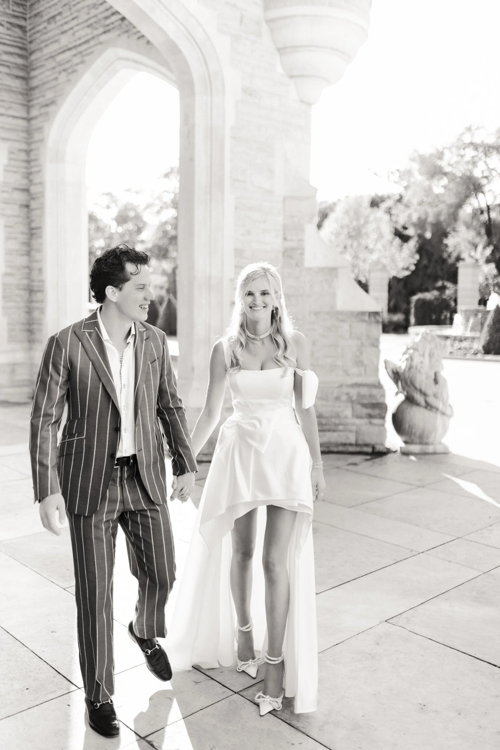 Black and white engagement portrait beneath Casa Loma stone arches