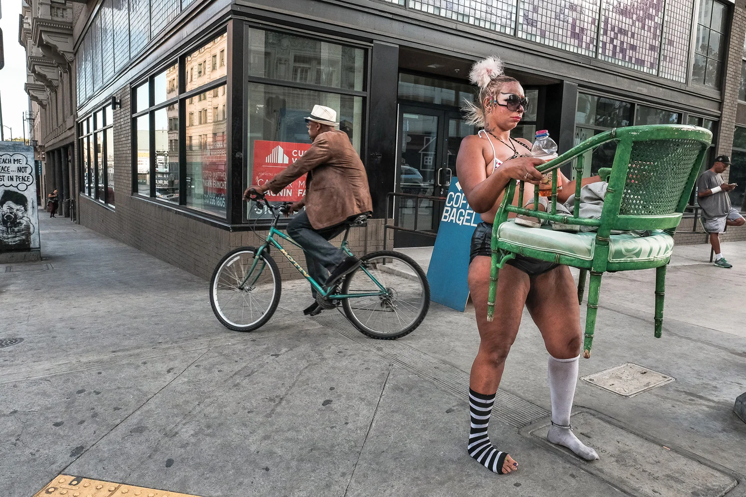 5th And Main St — a woman carries green chair, sits in various locations to solicit donations.