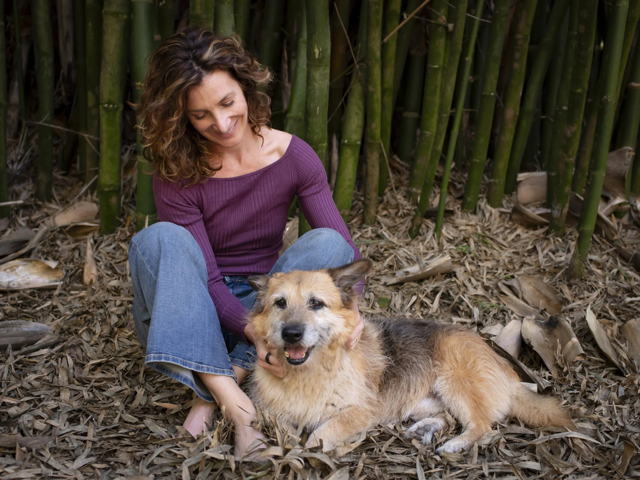 Dr. Amanda Alexander sitting with her dog and bamboo in the background