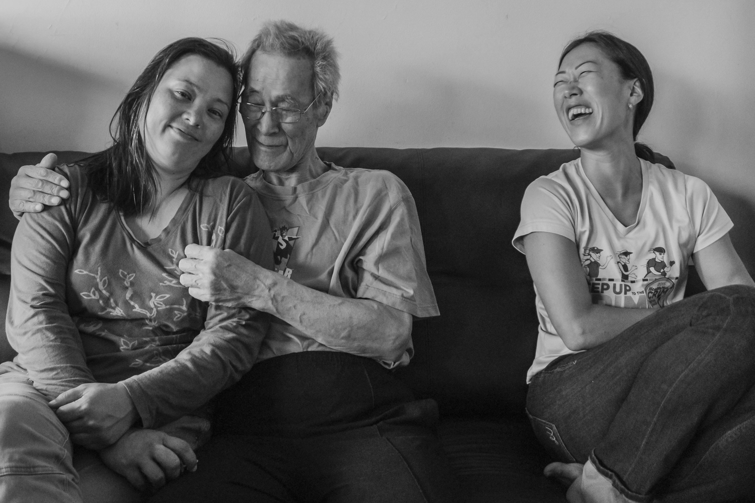 Terminally ill Chinsoo Kim is spending time with family visiting from out of state. He is sitting in his living room with his niece Celeste Pretzel (left) and his oldest daughter Nancy Kim (right). September 2, 2017. Chinsoo Kim’s apartment in the Crown Heights section of Brooklyn, NY. Photo by Sung Cho.