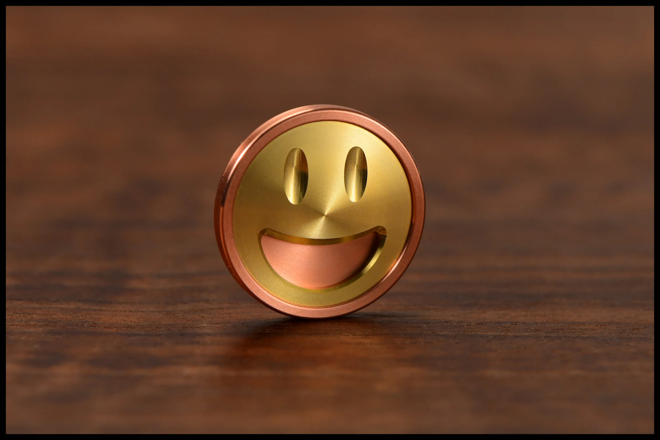 Copper Gambit coin with brass smiley emoji inlay