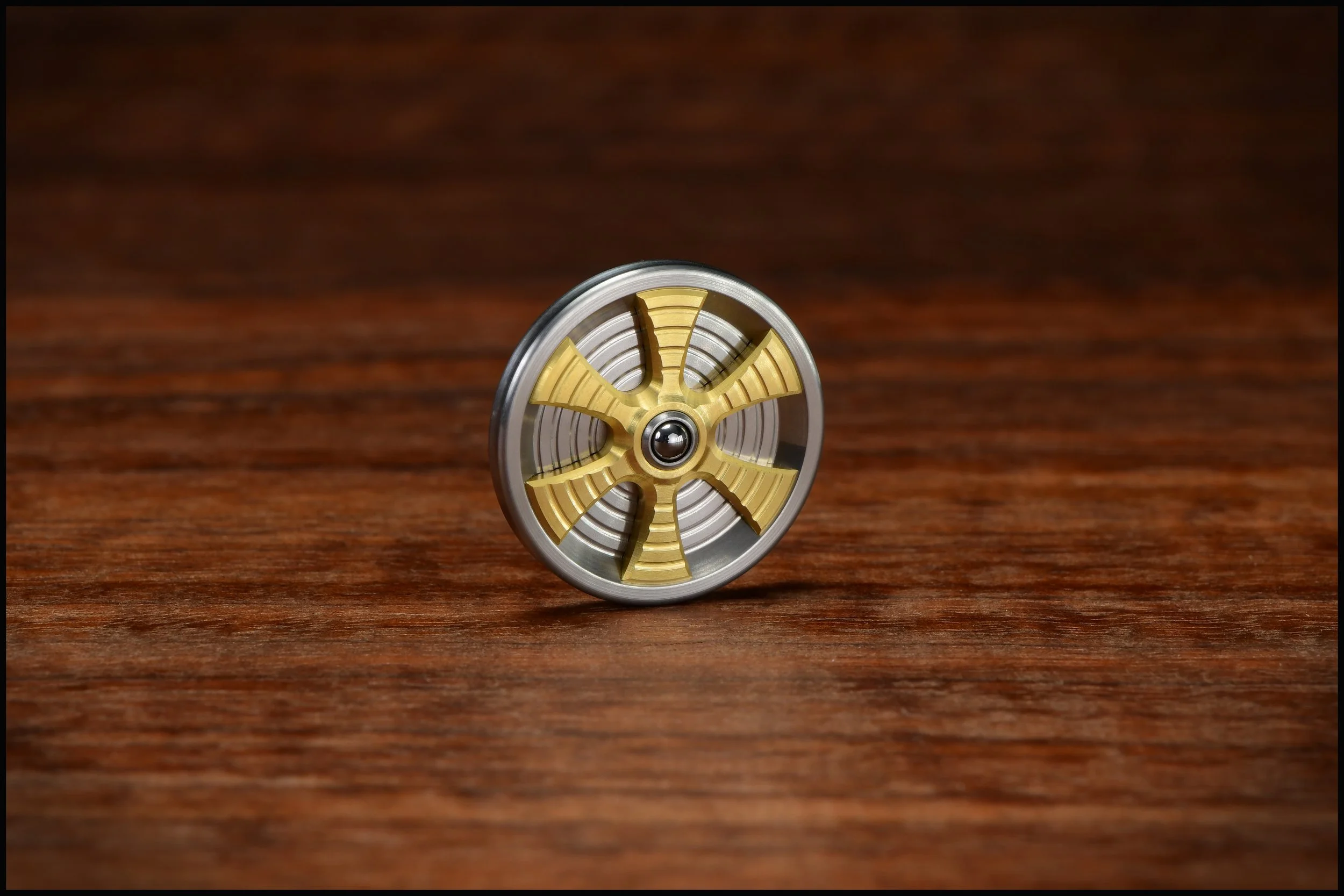 Stainless Steel Gambit coin with brass spoked inlay and a bearing ball