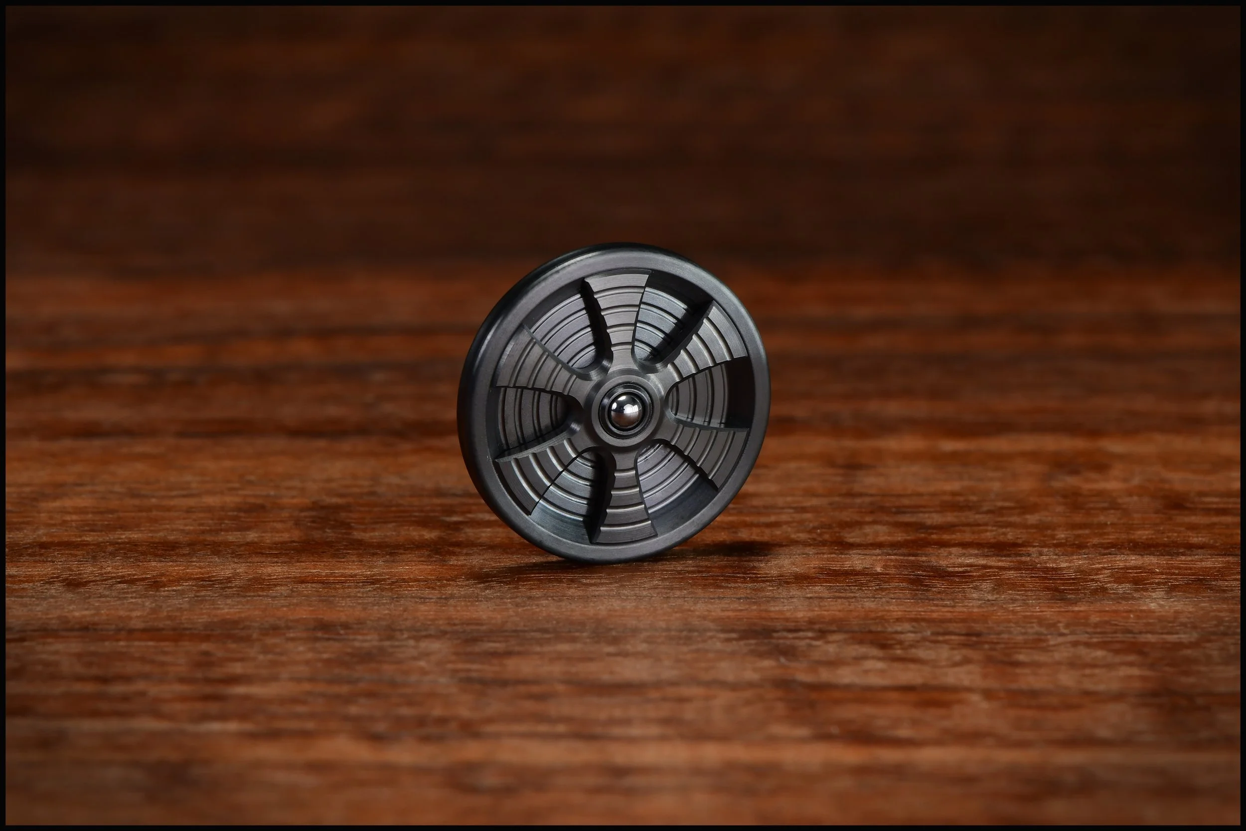 Zirc Gambit coin with a zirc spoked inlay and a bearing ball