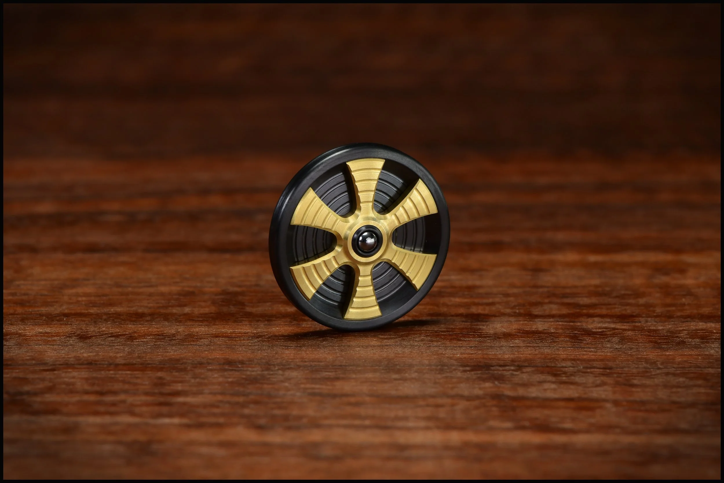 Zirc Gambit coin with brass spoked inlay and a bearing ball