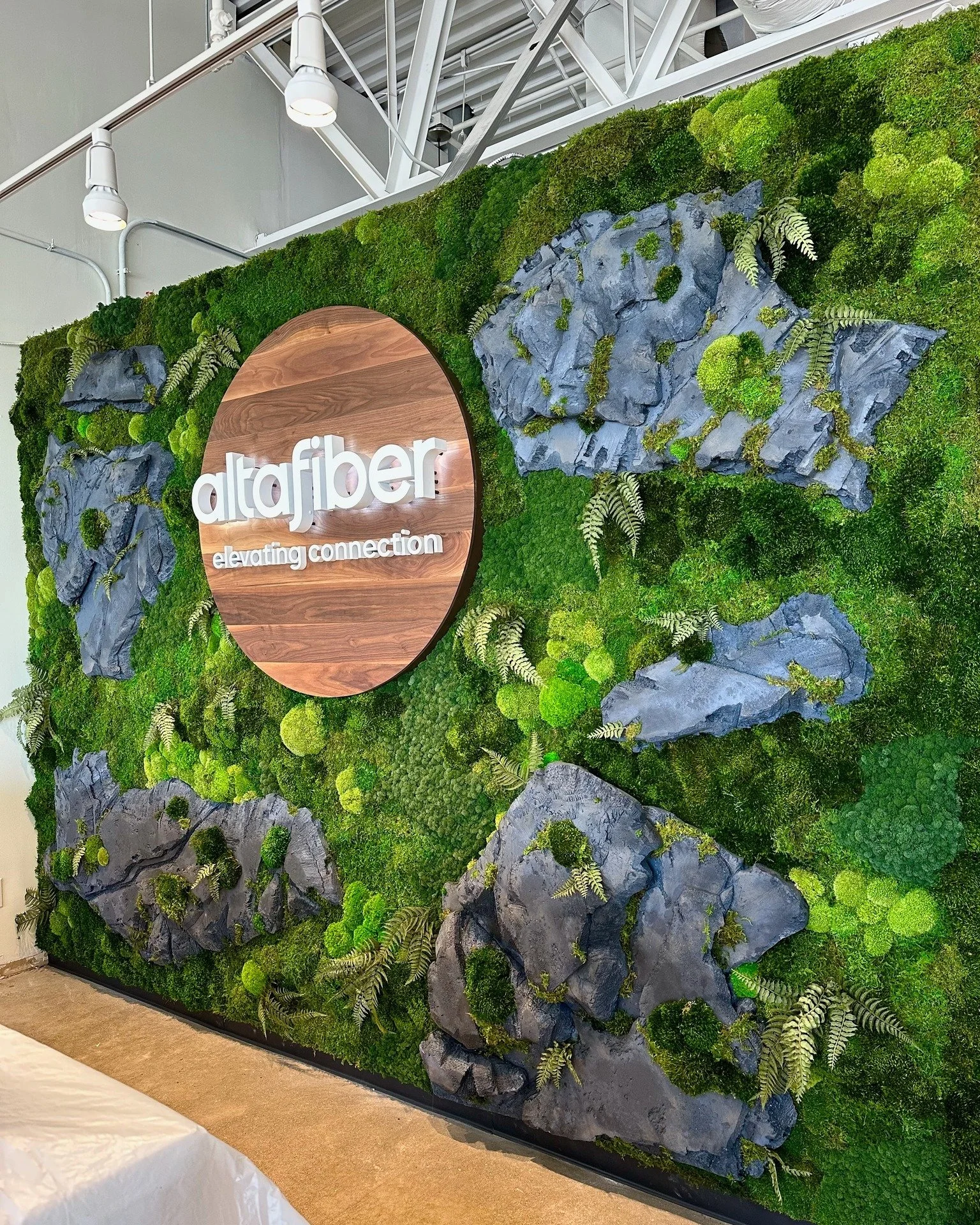 Layers of preserved moss and custom faux sculpted rocks bring the beauty of nature indoors to create an earthy-inspired backdrop that doubles as a powerful brand feature.

#greenwall #rockwall #custommade #logowall #biophilicdesign #plantwall #replic