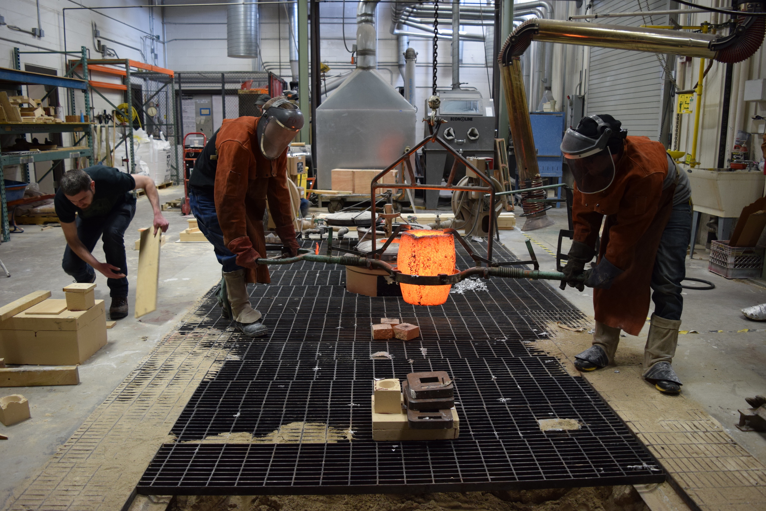  The crucible is slowly guided over to the sand pit with the molds. 