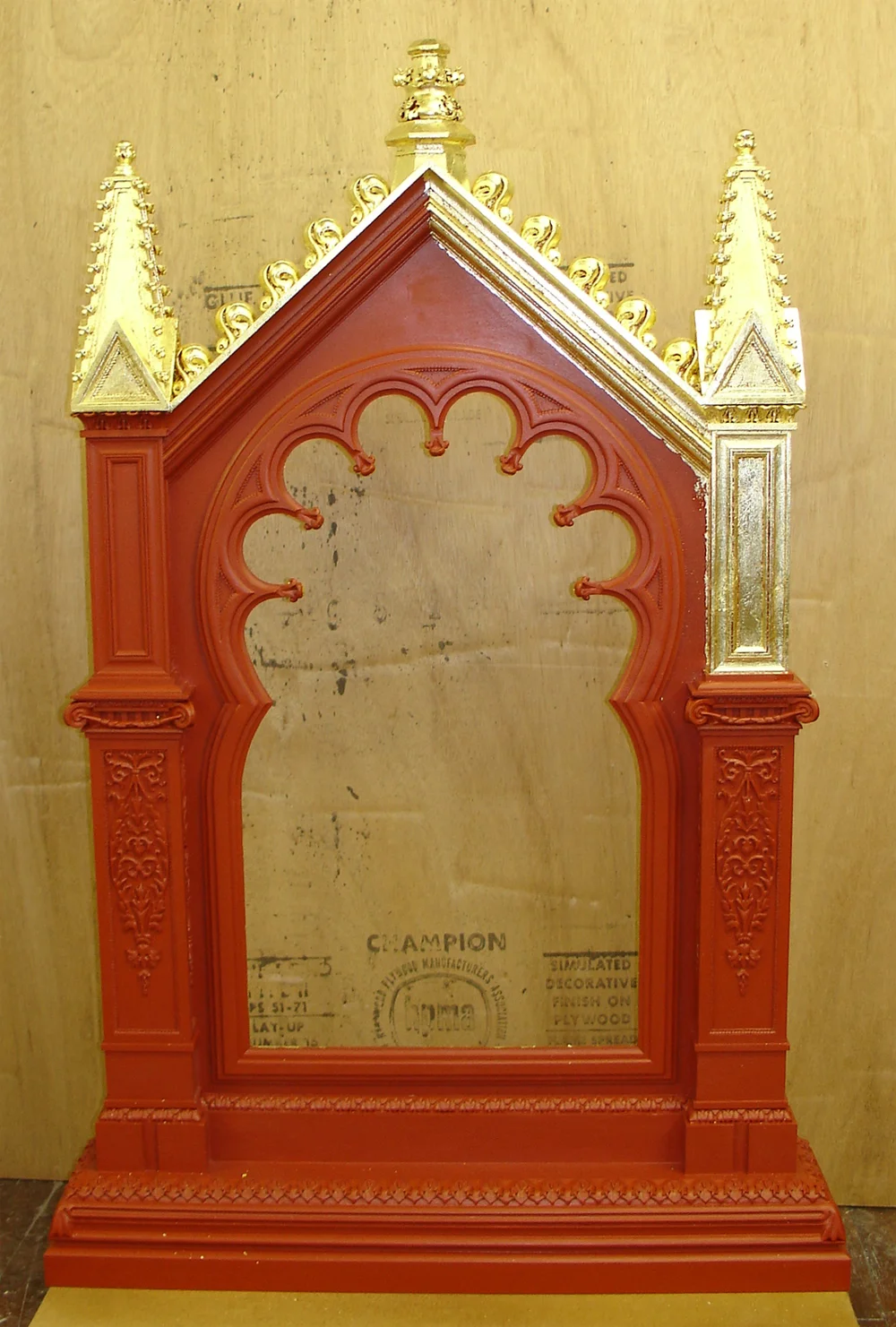 The frame with all of the ornament on, as well as the red bole, starting to be gold leaf gilded.