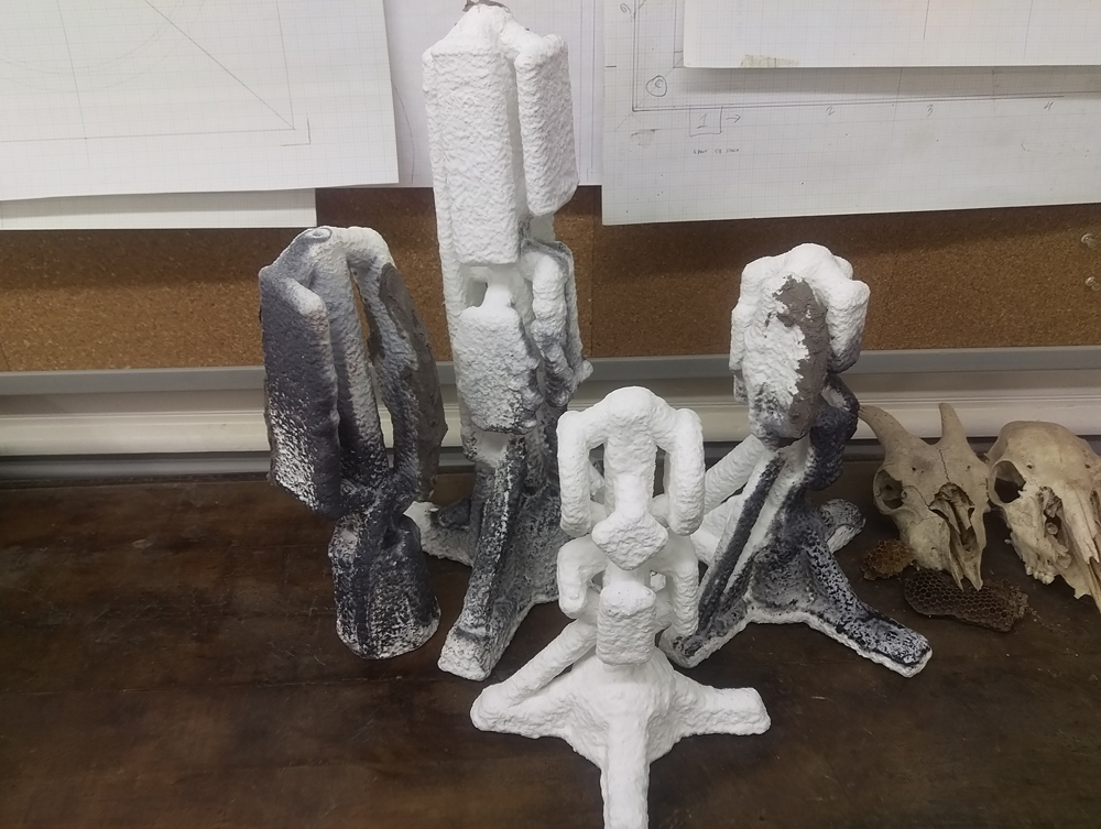  Four sprue trees of waxes with ceramic shell investment by Jeff Adams of inBronze foundry. The wax has been burned out and the molds are ready for bronze. 