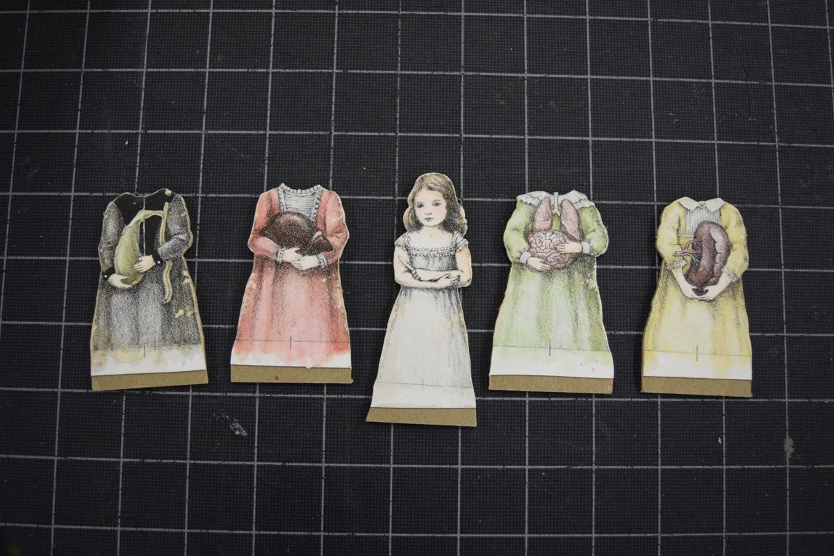 The finished dolls: Mounted to bookbinding board, cut out, and the edges distressed.