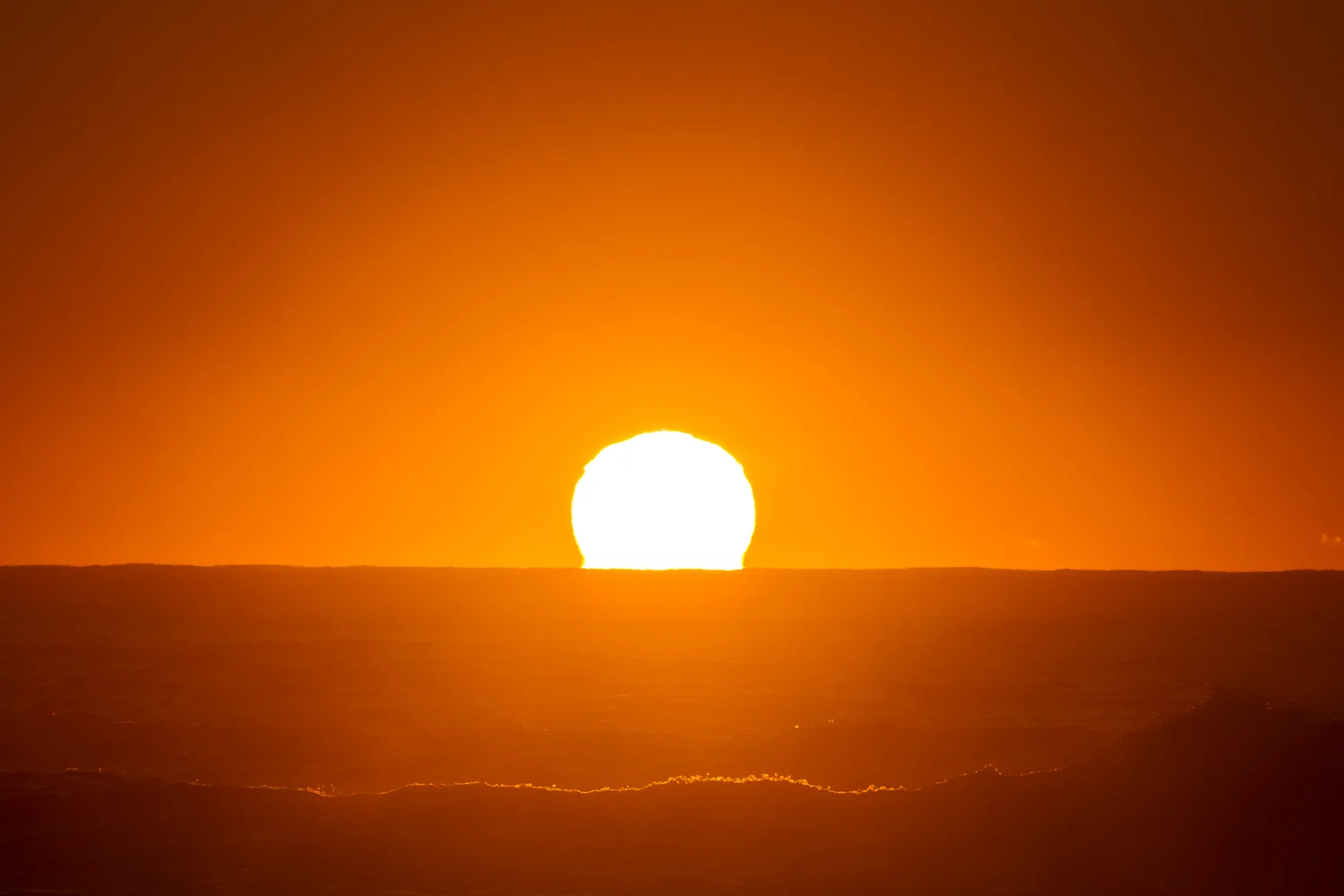 The sun peeking over the horizon, bringing life to another day of waves.