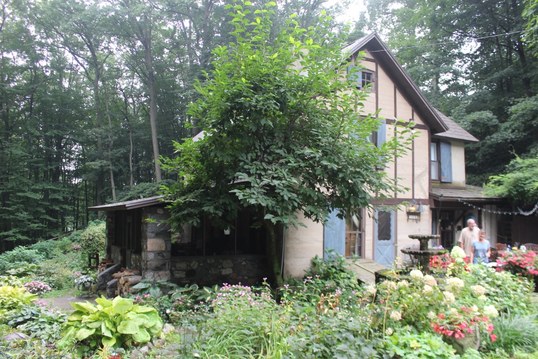 Original house has a graceful half-timbered style and original field stone porch. Sharon Bluhm and John Stivers in photo. 