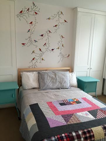 Bedroom at Wimbeldon Commons, London, England made cheery with colorful side tables, vintage style quilt and bird wall art