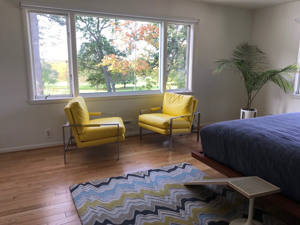 MASTER BEDROOM WITH YELLOW CHAIRS AND VIEW OF SUNSET OVER GOLF CLUB