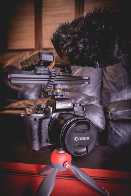 Canon EOS M5 Mirrorless Camera w/ attached 11-22mm f/4 lens and Manfrotto PIXI mini tripod.. Rig consists a slider mount, Sennheiser MKE400 microphone w/ windscreen, and top handle 