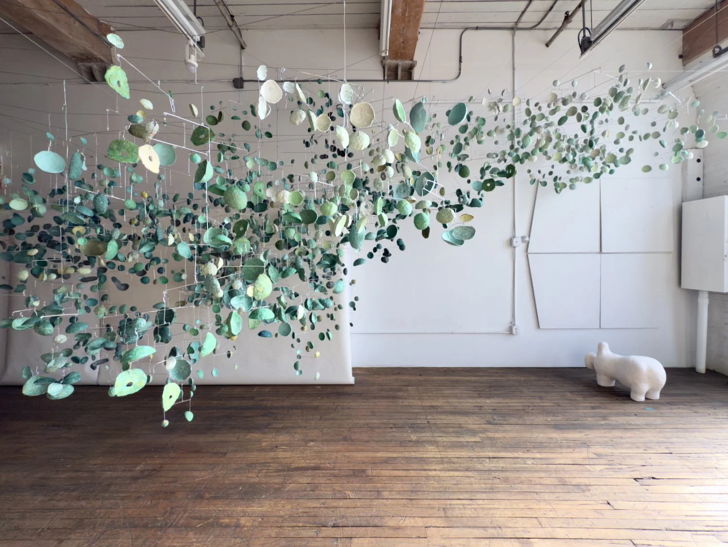 Green Mobiles, 2025. Paper pulp and wire, 84 x 360 x 144 inches (213 x 914 x 366 cm)  Installation view with 35 mobiles