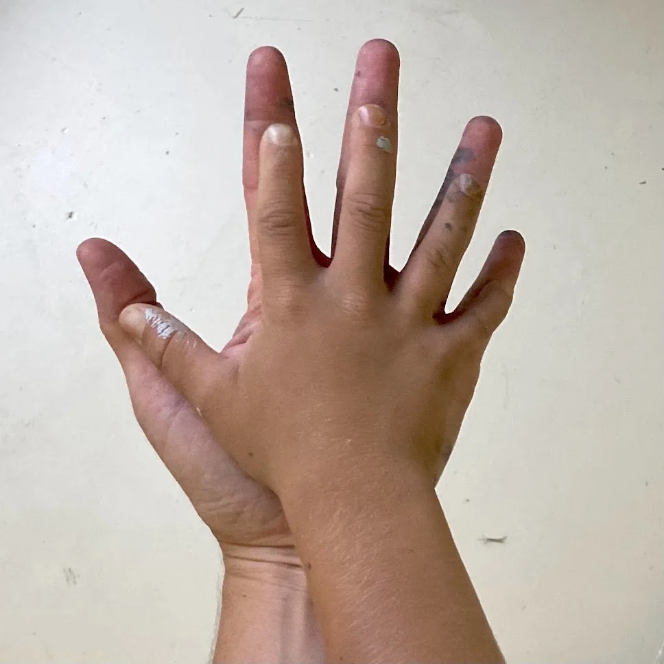 A hand with fingers spread out, resting on a plain, light-colored surface.