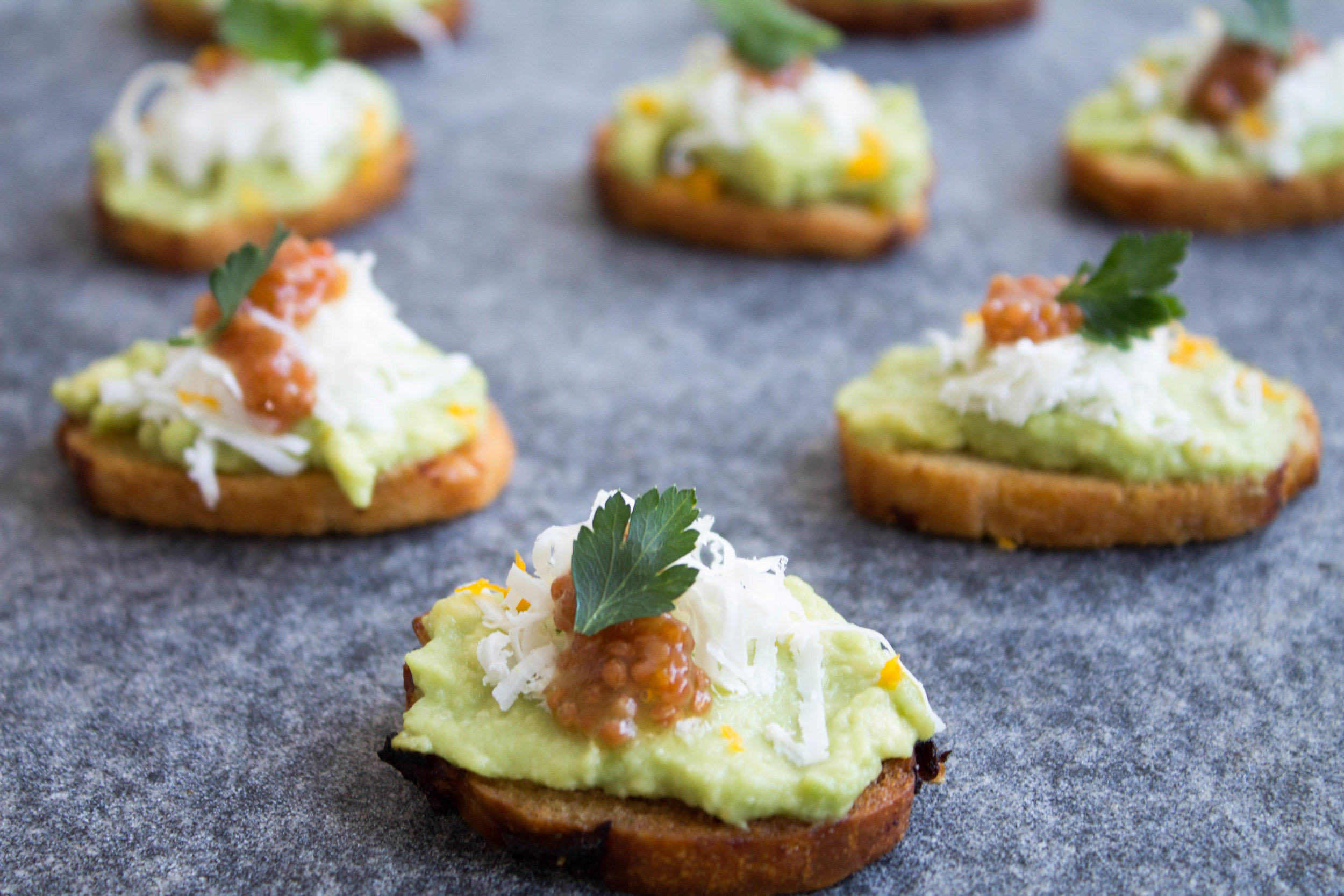 Avocado, ricotta salata, and pickled mustard seeds on onion crostini