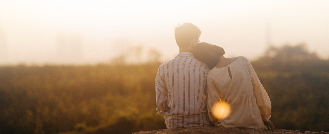 Couple sitting together outdoors in warm evening light