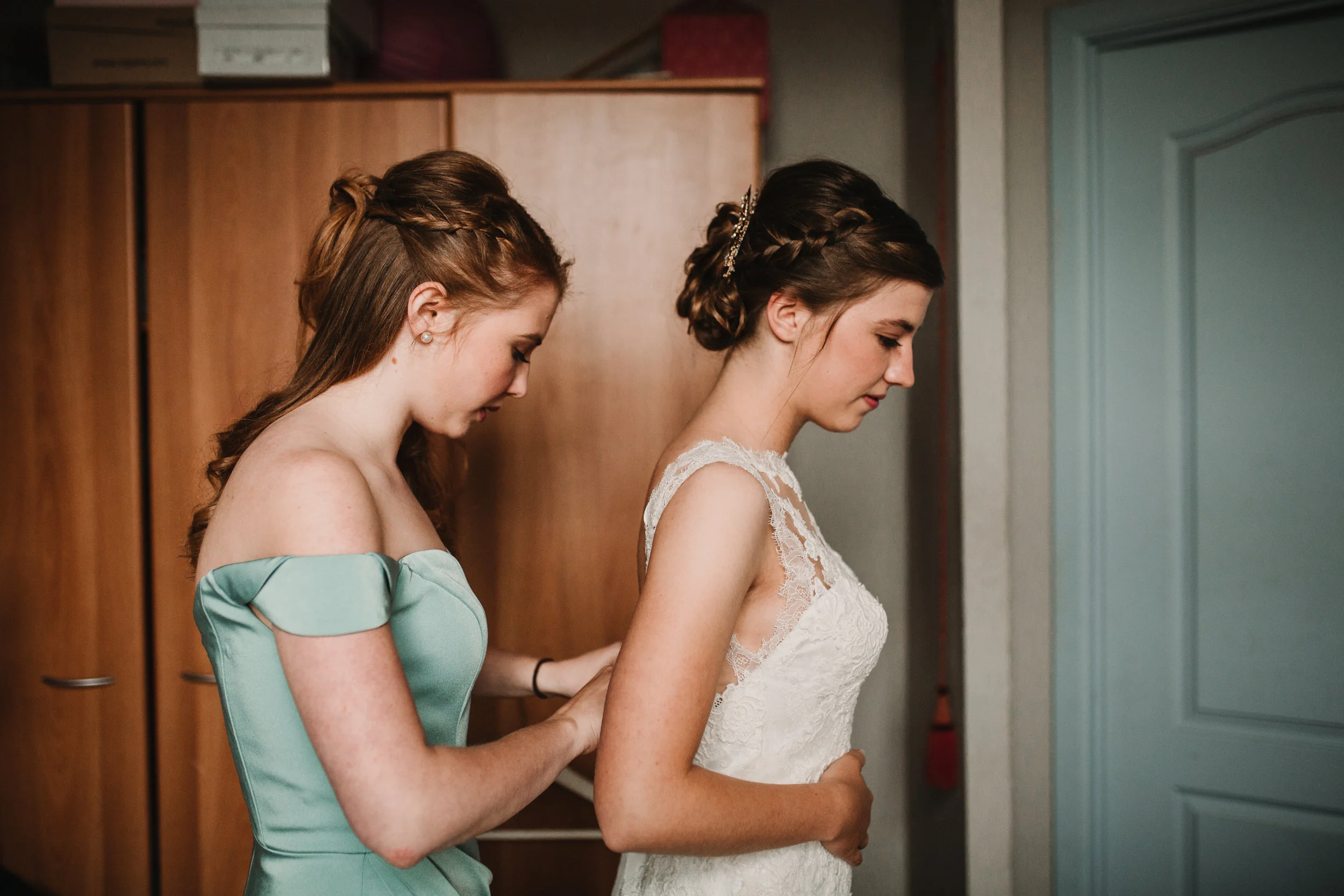 Bridesmaid helping bride into dress before city hall ceremony in Ghent, Belgium