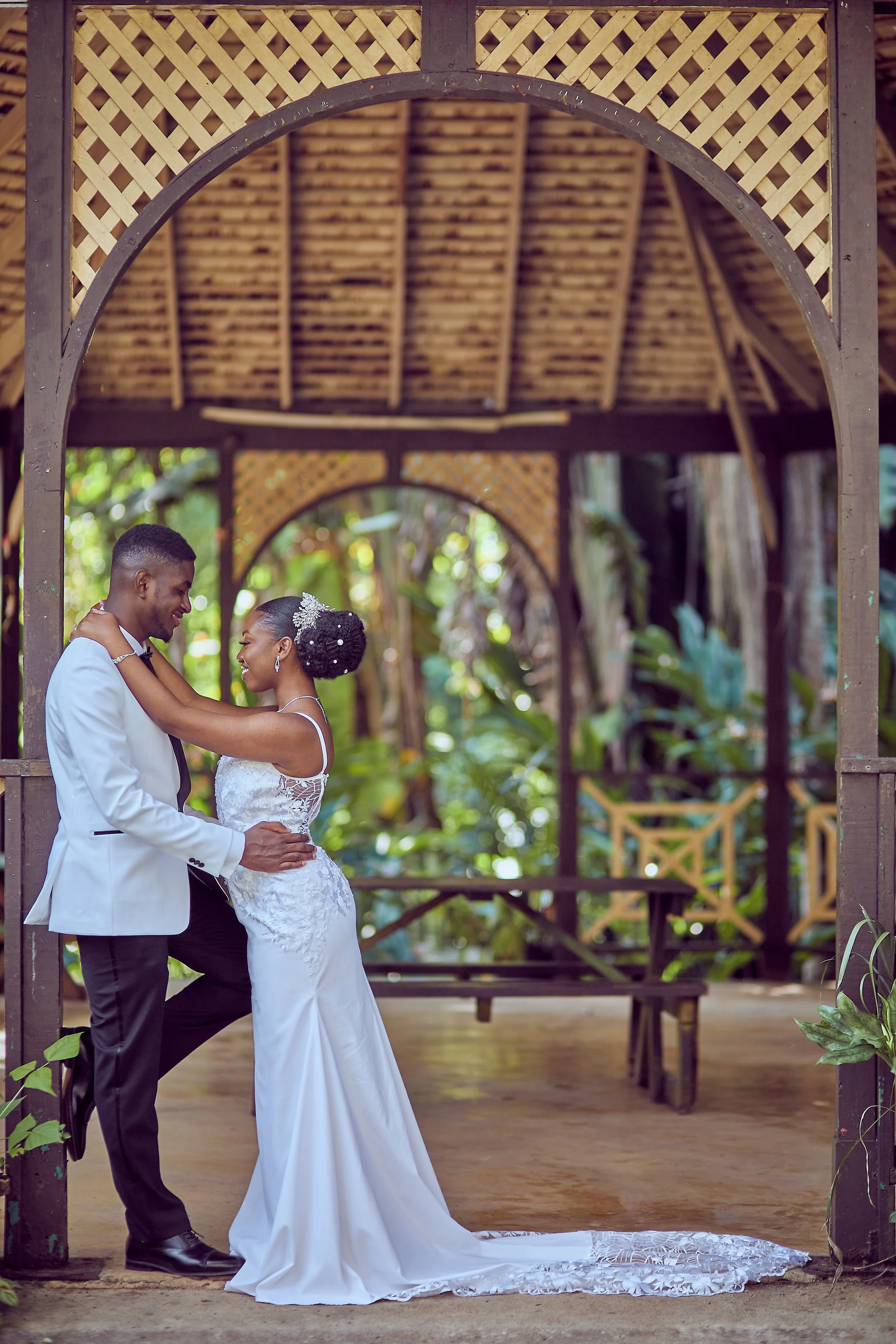 A bride and groom dancing in a tropical outdoor gazebo surrounded by greenery.