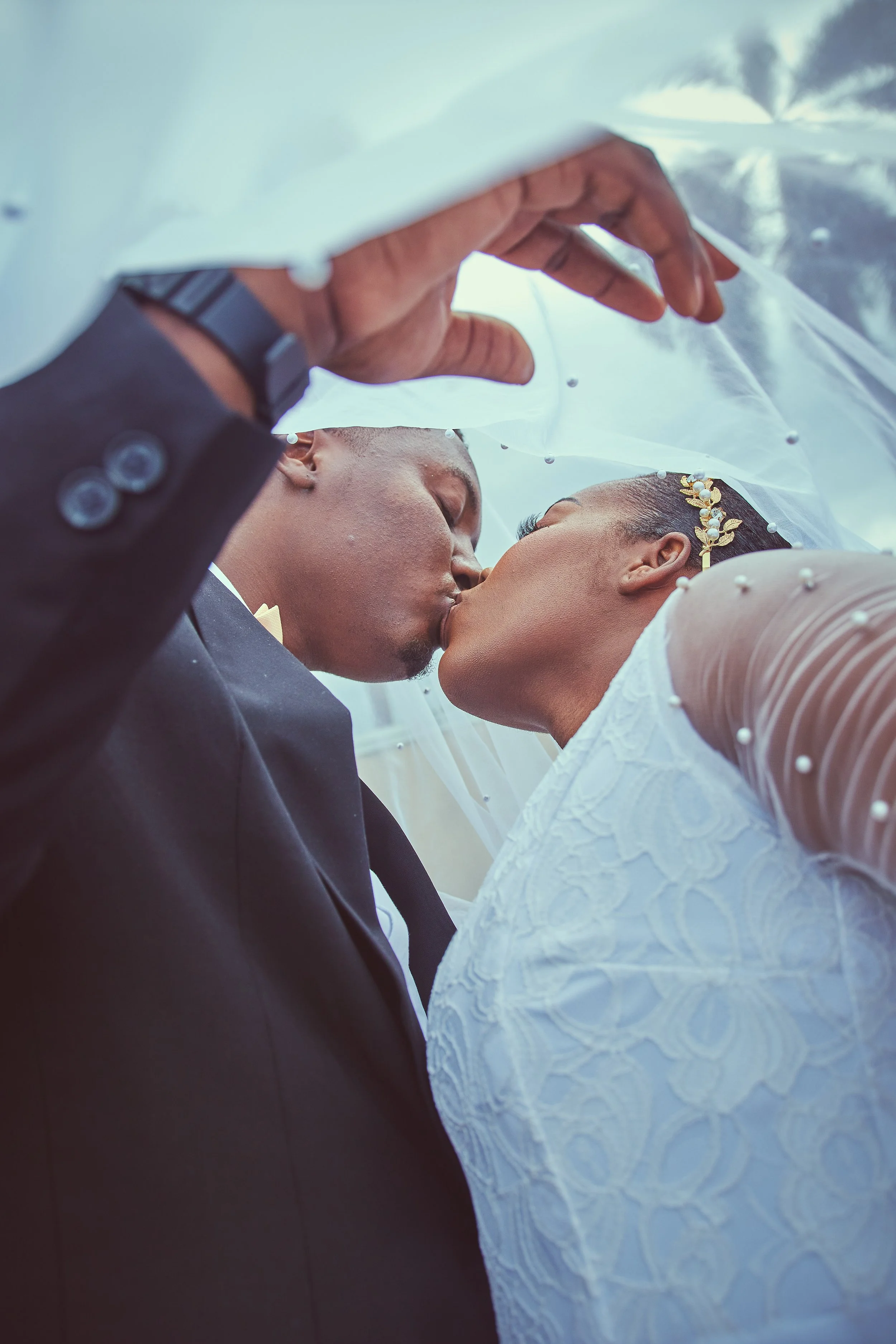 A bride and groom sharing a kiss under a wedding veil.