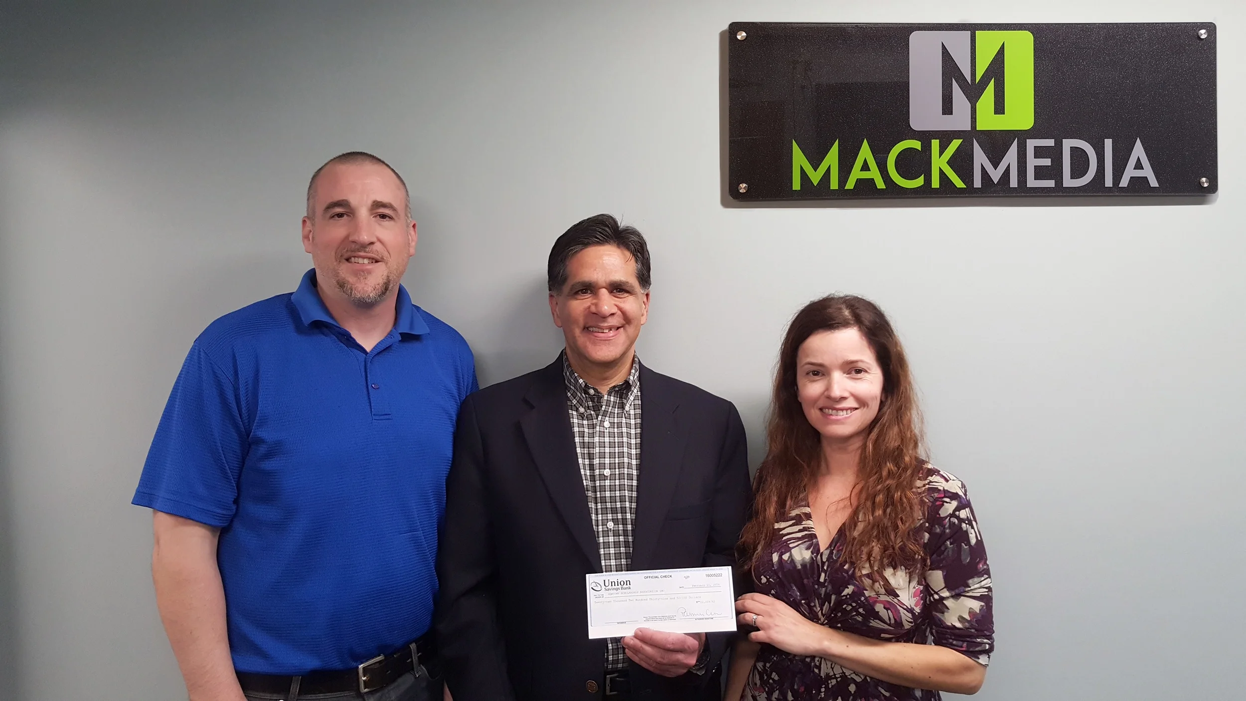 Newtown Scholarship Association President, Glenn Nanavaty (center), accepts a donation in the amount $22,239.52 from Scott and Carla Johnson, owners of Mack Media Group and founders of the Newtown Strong Fund.